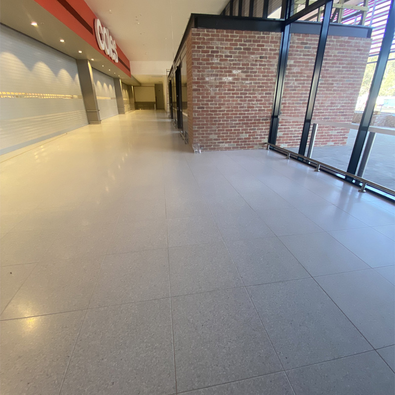 Large pale floor tiles in a shopping centre walkway outside Coles