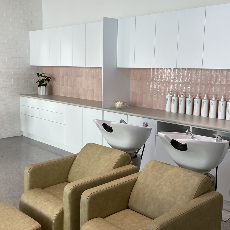 Pink wall tiles behind hair salon wash basins and chairs