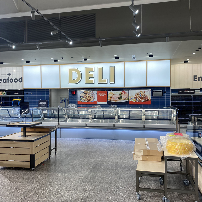 Speckled floor tiles in front of a supermarket deli counter with blue wall tiles