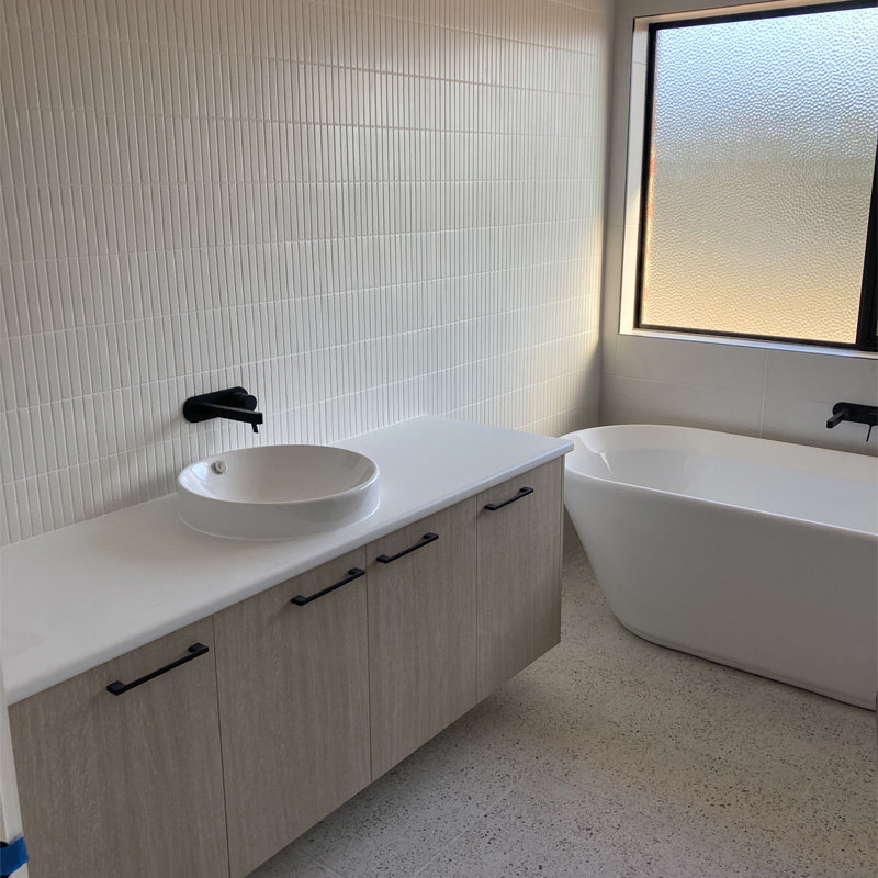 White finger tile wall above a vanity beside a freestanding bath