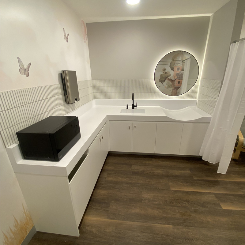 White L-shaped bench and finger tile splashback below a lit round mirror