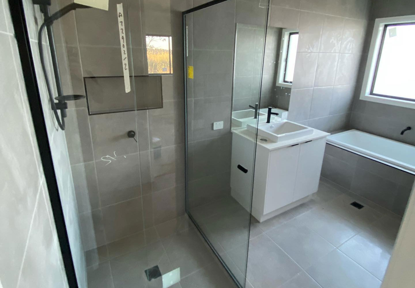 home-magnifier Tiled bathroom with a glass shower screen, white vanity and built-in bath